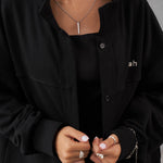 Black oversized French Terry overshirt with button detailing, paired with a black top and layered necklaces.