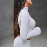 long sleeve grey crop top with a high neckline and bell sleeves.