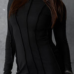 Black long-sleeve dress worn by a model against a gray background