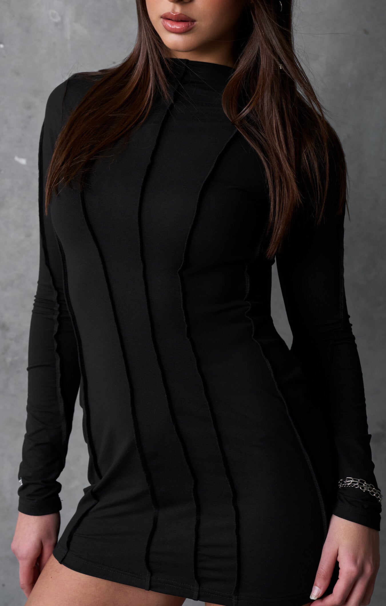 Black long-sleeve dress worn by a model against a gray background